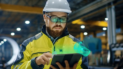 Lavoratore di attrezzature pesanti in un elmetto utilizzando un iPad